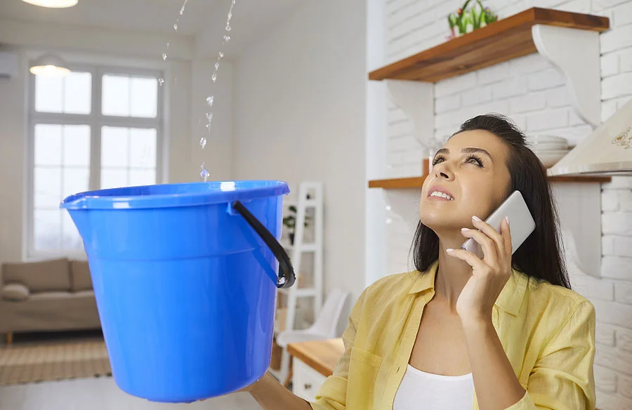Woman-With-Leaky-Roof Woman using a bucket to catch leak in roof