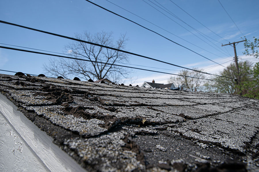 Home Roof with Damaged Asphalt Shingles in need of Replacement
